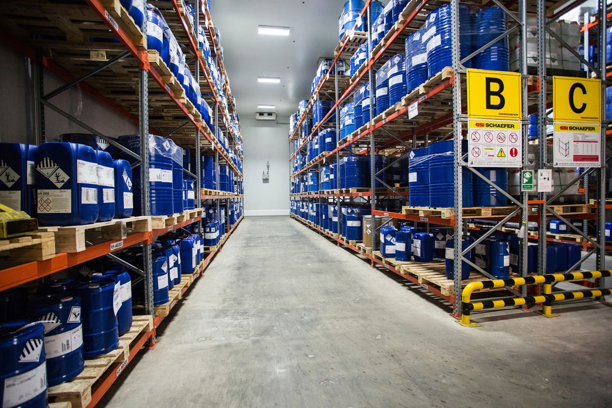Warehouse aisle with racks of blue chemical drums