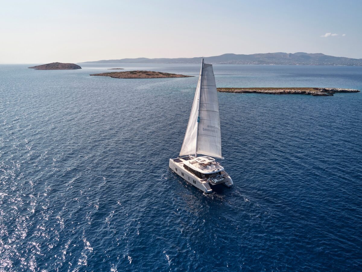 Sailing catamaran under sail on open water near small islands