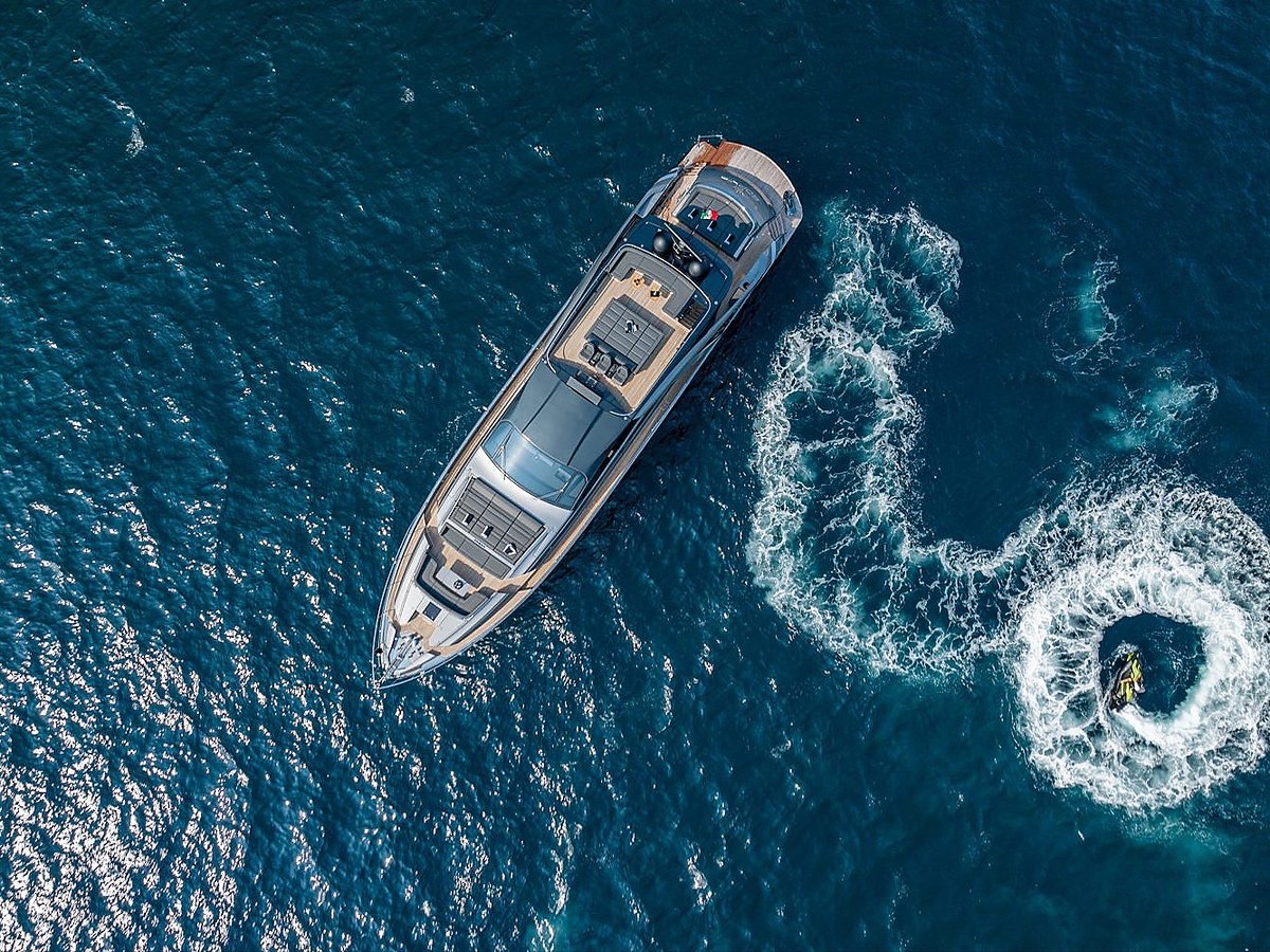 Yacht seen from above with a jet ski leaving a wake beside it
